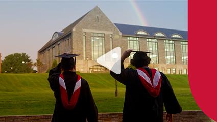 Image of students throwing graduation caps with a rainbow over the library.